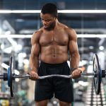 Hombre negro atlético que trabaja en los brazos y los músculos del torax