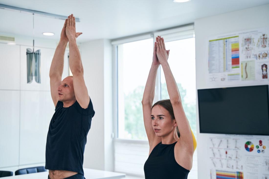 Profesora de yoga ayudando a una alumna