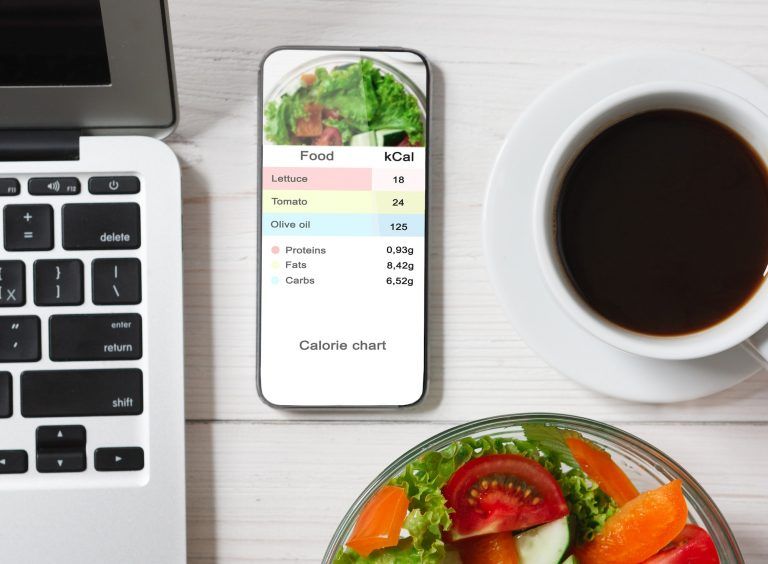 Contador de calorias. Teléfono inteligente con aplicación para contar calorías sobre la mesa plana