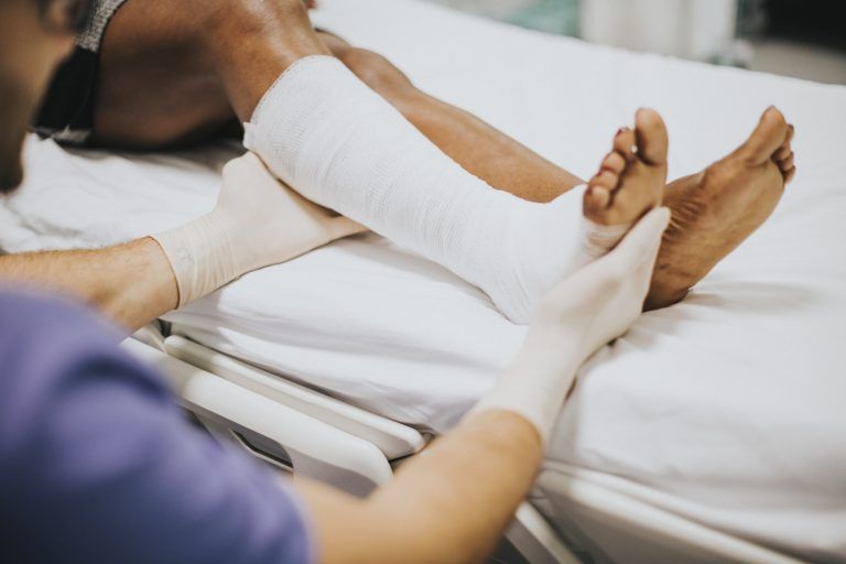 Doctor ayudando a una paciente con una pierna fracturada