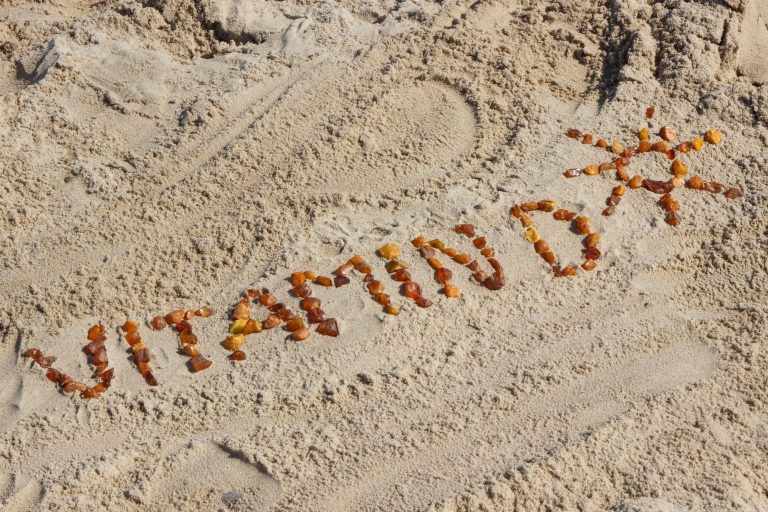 Inscripción vitamina D con forma de sol en la arena en la playa