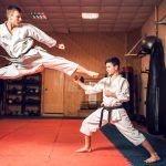Maestros de artes marciales practican patada en salto