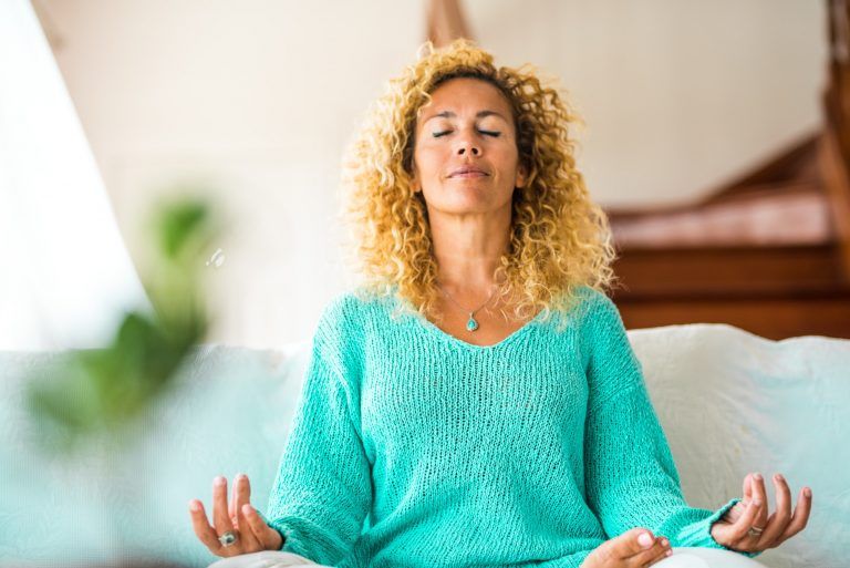 mujer haciendo yoga en casa y relajándose en el sofá sola en el interior - estilo de vida saludable