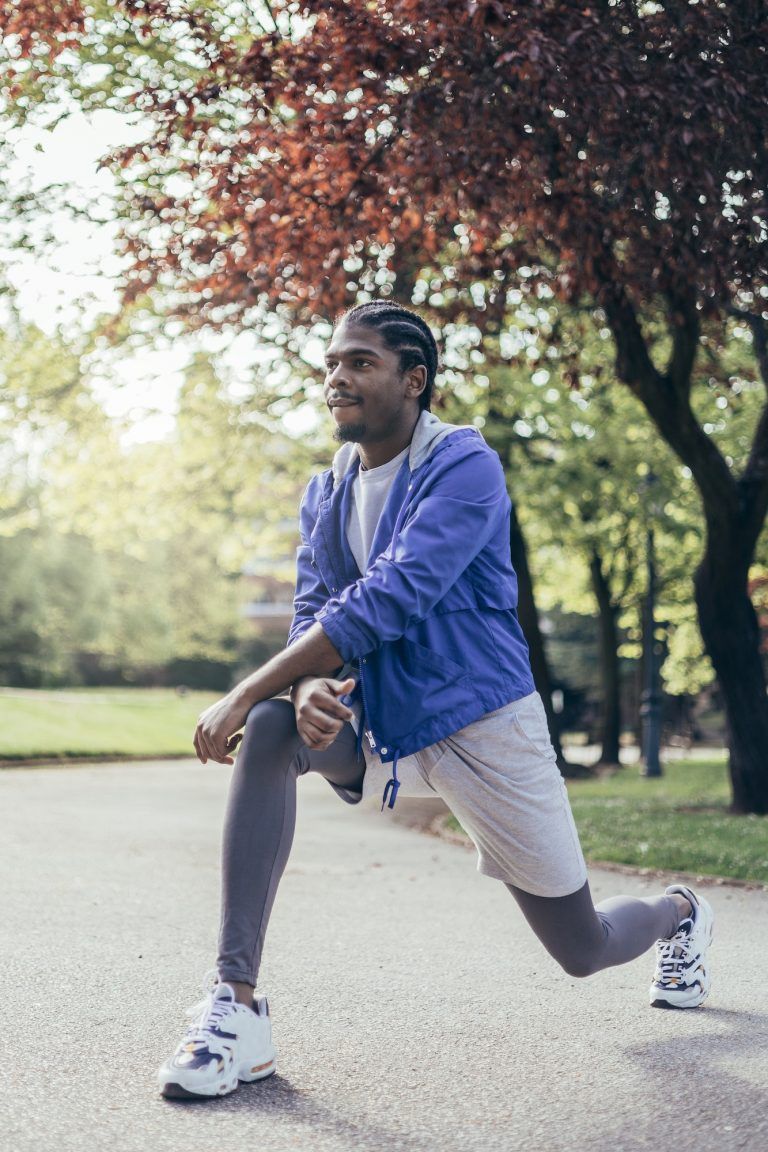 joven afroamericano estirando cuádriceps antes de correr en el parque