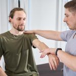 Doctor militar ayuda a un soldado a desarrollar un brazo herido