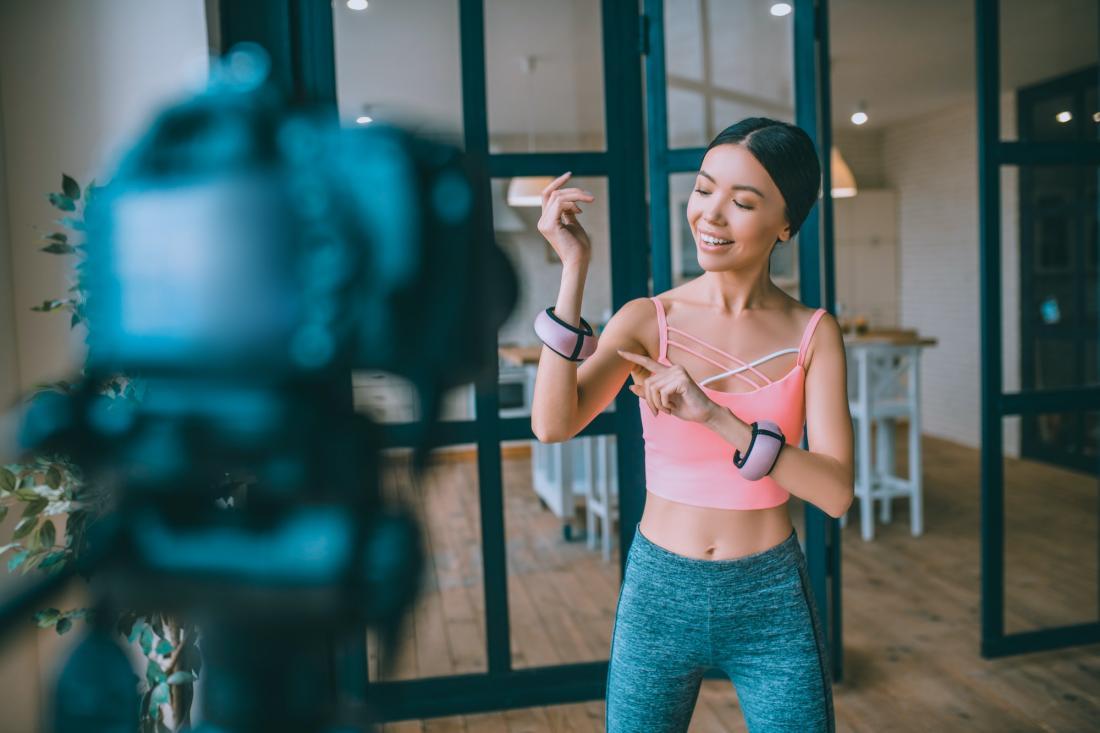 Blogger de fitness satisfecho que cuenta a sus seguidores sobre las pesas en los brazos