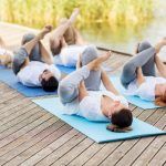 people making yoga in supine pigeon pose outdoors
