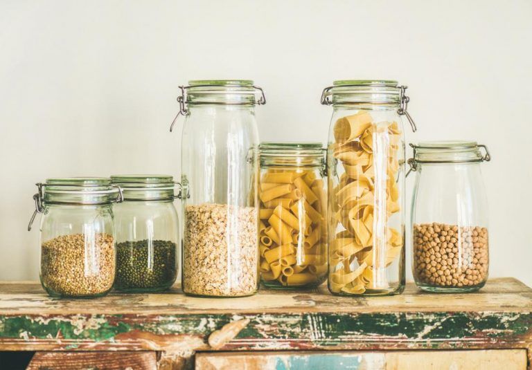 Uncooked cereals, grains, beans and pasta in jars on table
