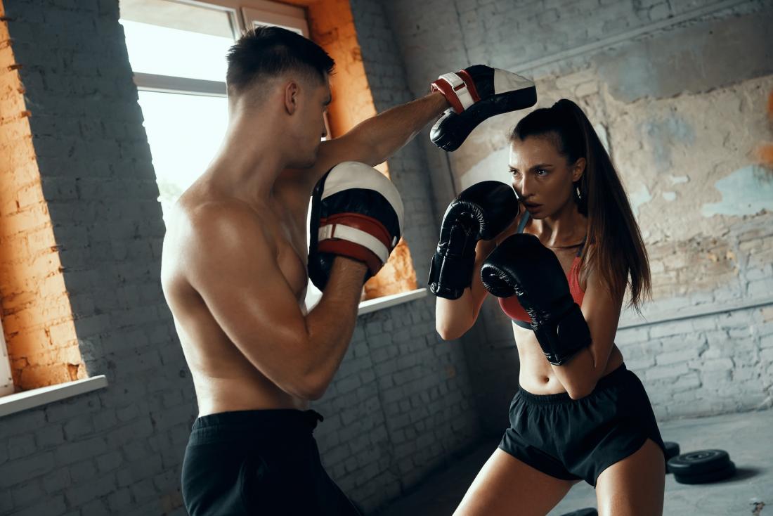 Mujer entrenando boxeo con su entrenador