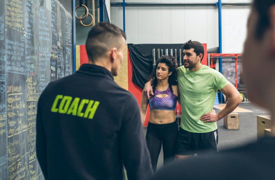 Entrenador personal dando indicaciones a dos alumnos en el gimnasio