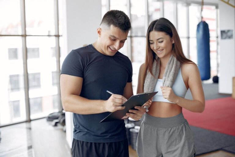 Entrenador revisando el plan con una clienta en una tablet