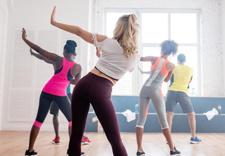 Vista trasera de bailarines multiétnicos de zumba realizando movimientos en el estudio de baile