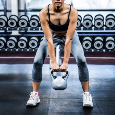 Mujer levantando pesa rusa en el gym