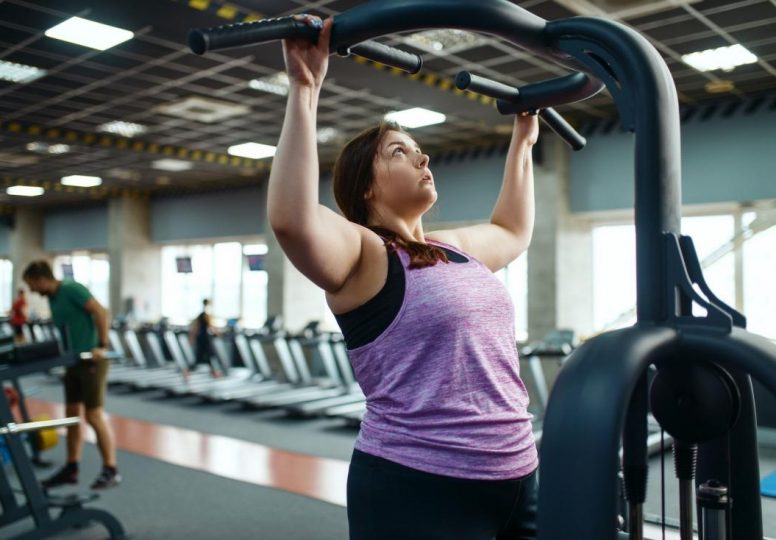 Mujer con sobrepeso en máquina de ejercicio en el gimnasio