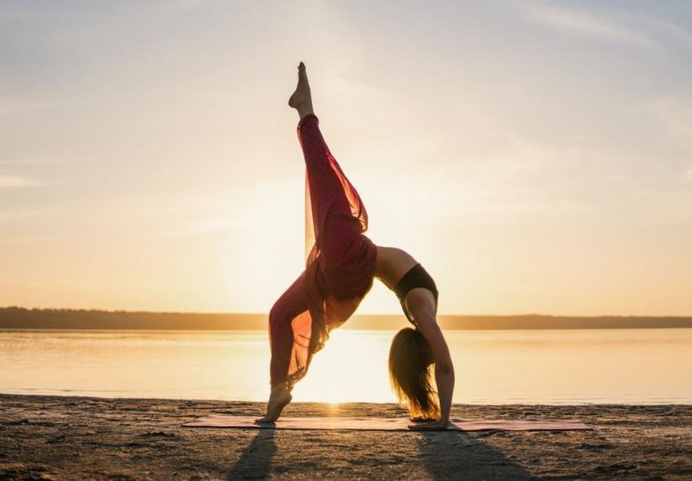 Mujer de silueta yoga en la playa al atardecer