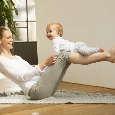 Mujer balanceando un bebe en sus piernas