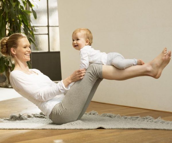 Mujer balanceando un bebe en sus piernas