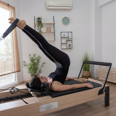 Mujer en valencia joven haciendo ejercicio en la cama del reformador de pilates